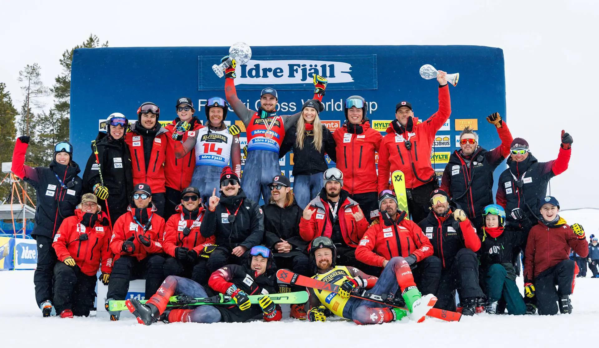 une photo de groupe de skieurs célébrant ensemble dans la neige avec leurs trophées